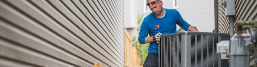 An Action Furnace technician shifts a new air conditioner into place.