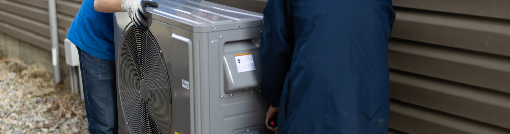 A new high-efficiency Comfortec heat pump is carefully moved into place.