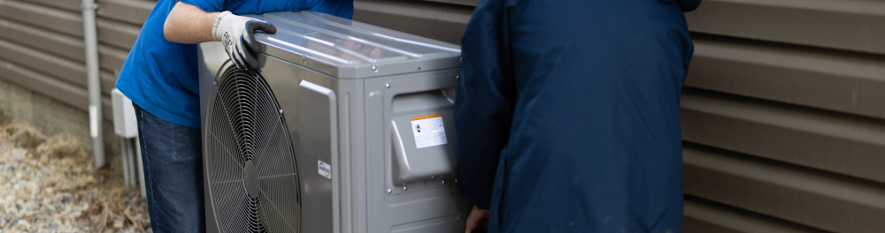 A heat pump is carefully inspected in it's new installation location.